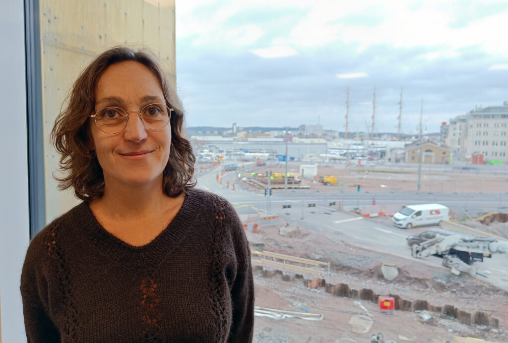 Anna Javér vid kulturförvaltningen i Göteborg står framför ett fönster; i bakgrunden syns Barken Viking.