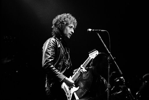 Svartvitt foto föreställande Bob Dylan på en konsert i Toronto, han håller i en gitarr. 