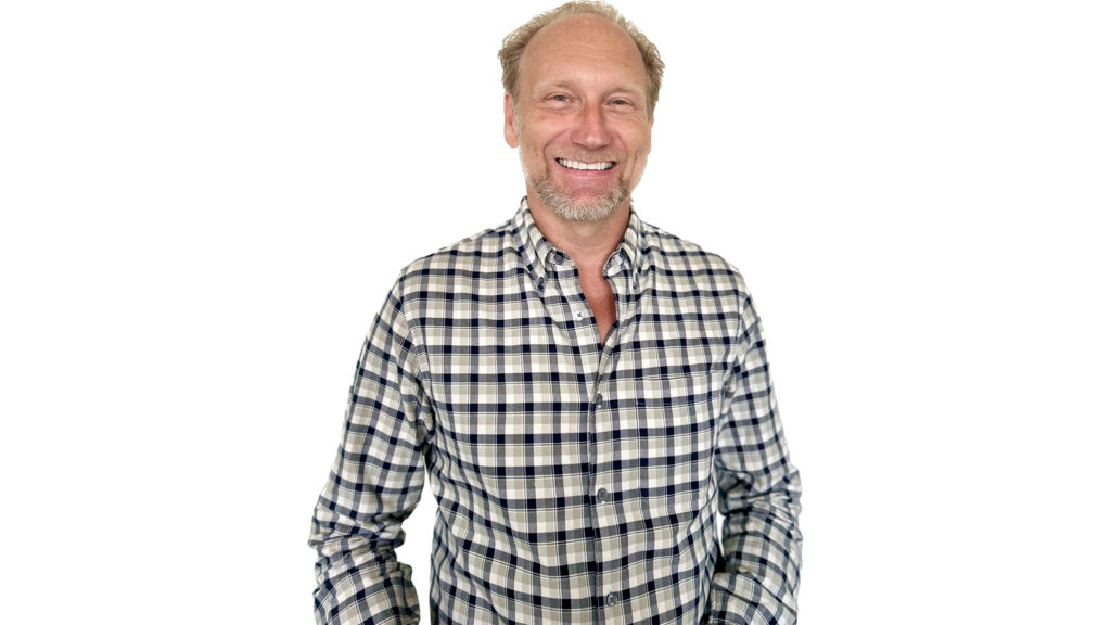 En leende man i rutig skjorta, vit bakgrund.