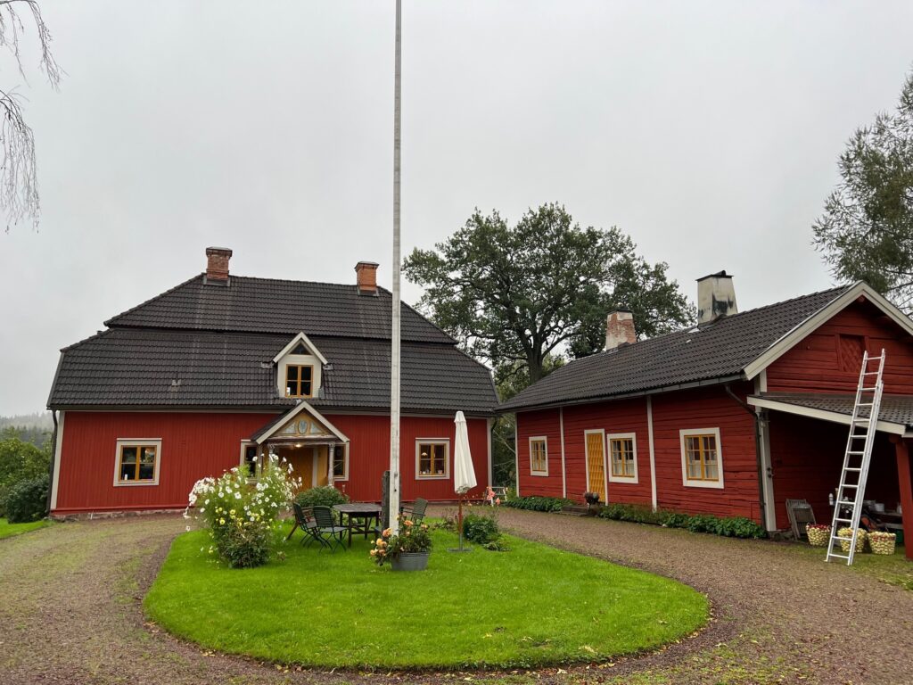 En gård med två röda hus och en grön rundel av gräs framför.