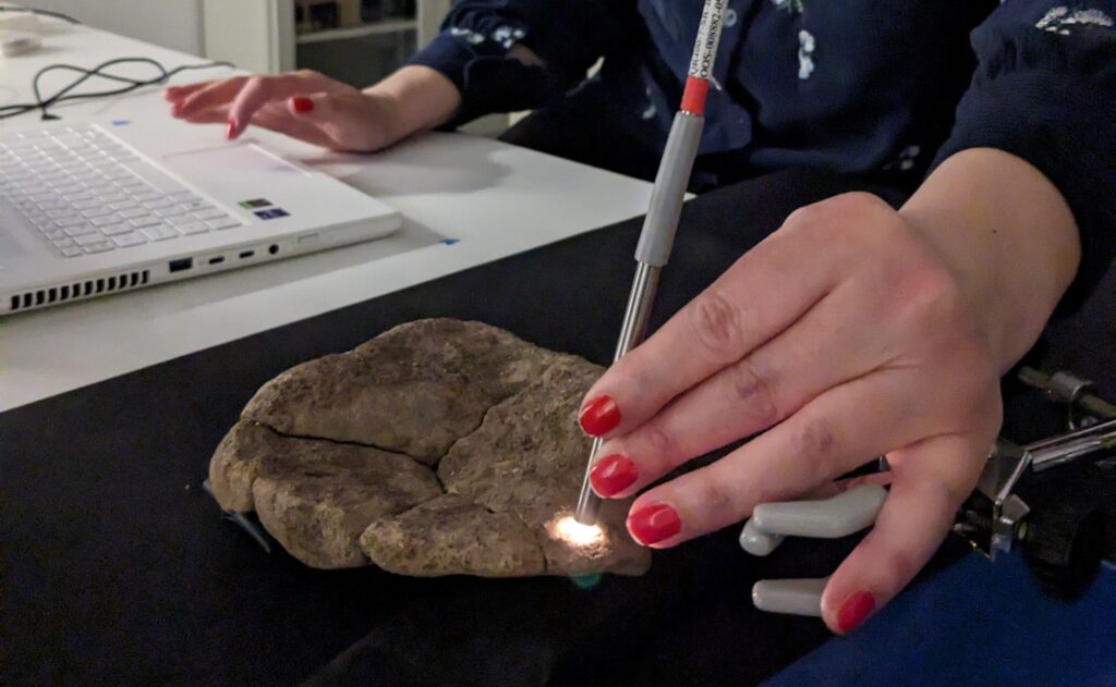 En hand som håller i en stav som lyser på en sten