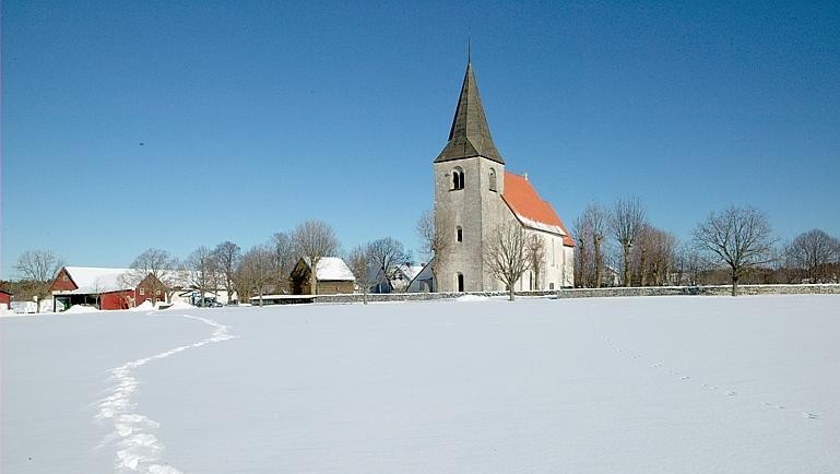 En kyrka på avstånd i ett snöigt landskap.