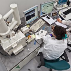 Två kvinnor framför ett skrivbord med SEM-mikroskop.