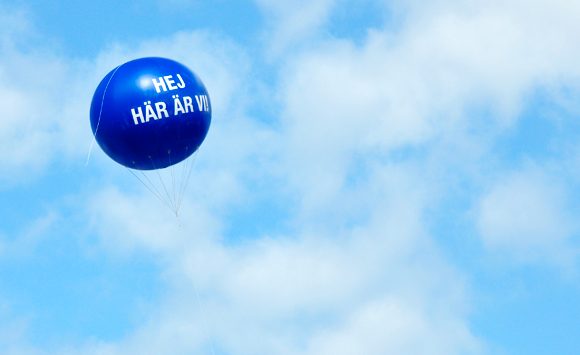 Ballong med texten Här är vi svävar på himlen.