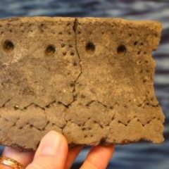 Hand som håller en bit gammal keramik