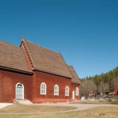 Bilden visar en kyrka av trä med klockstapel intill.