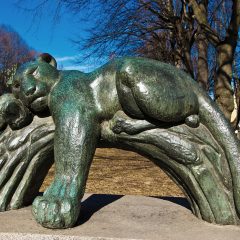 Bronsstaty där en panter hänger över trädstam