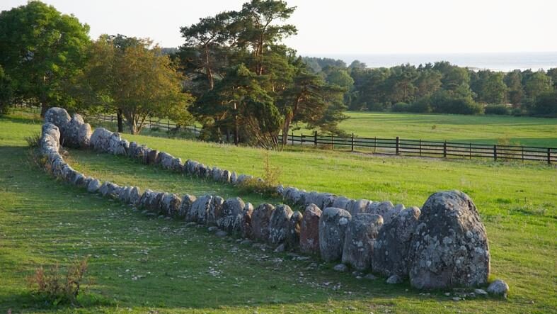 Ett stort antal högresta stenar står i grönskan på en slänt, de liknar formen av en båt.