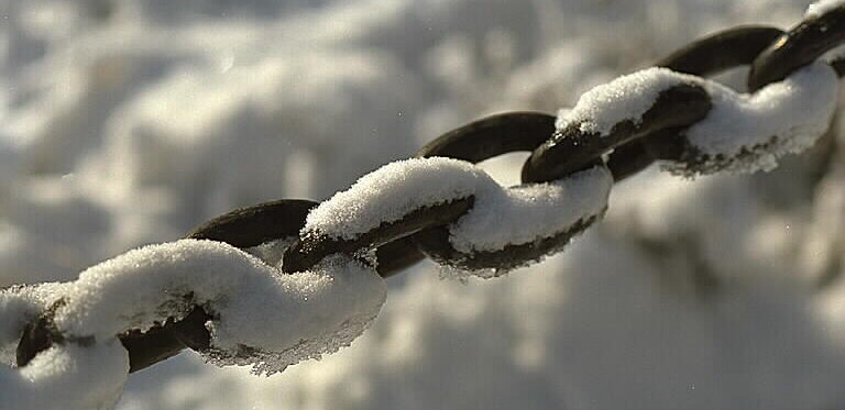 Närbild på kedjans ringar med snö på.