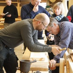 Deltagare på ett hantverksseminarium vid en hyvelbänk.