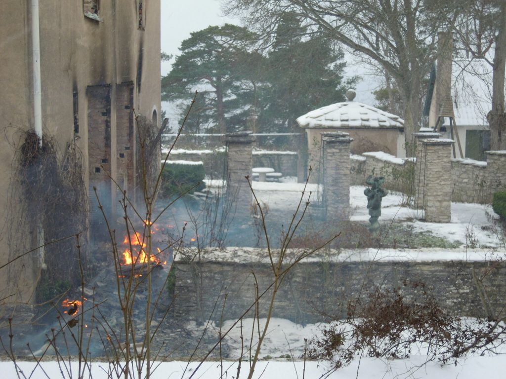 Stenhus med trädgård som har skadats av brand.