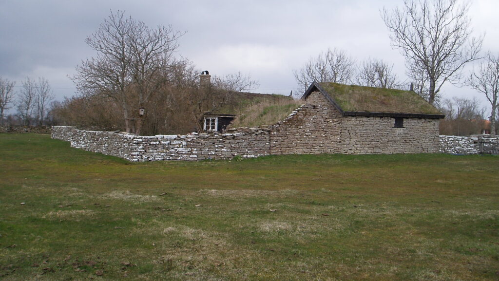 Stenhus med mossbevuxna tak och runt om en mur.