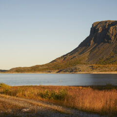 Ett högt berg sluttar ned mot en sjö där himlen speglar sig.