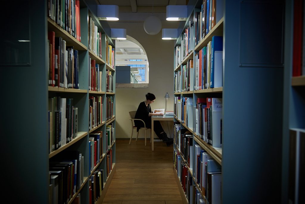 Kvinna som läser i biblioteket