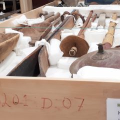 Ett stort antal föremål av trä och metall ligger förpackade i ett emballage av trä.