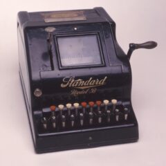 En svart gammal räknemaskin från förra sekelskiftet. Den heter Standard modelll B och kommer från Machine Co i USA. Den har knappar och en vev.