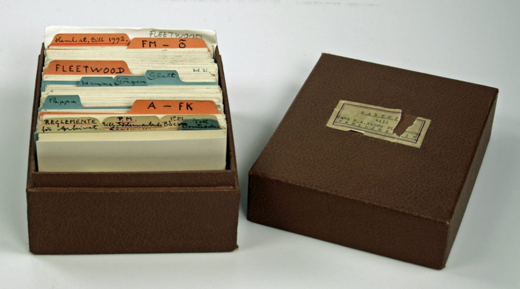 Liten brun kartotekslåda med katalogkort med texten Kartotek till Carl R. A. G:son Fleetwoods familjearkiv klistrad på locket.