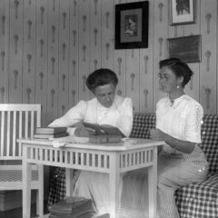 Rumsbild, två kvinnor vid bord, läsande. 1911.