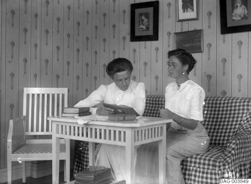 Rumsbild, två kvinnor vid bord, läsande. 1911.