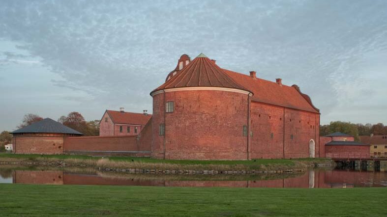 Stor slottsbyggnad i tegel med ett runt citadell på gaveln.