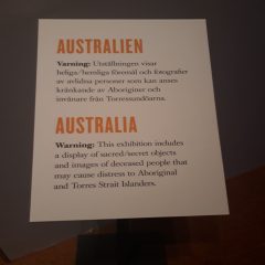 Skylt med texten Varning: Utställningen visar heliga/hemliga föremål och fotografier av avlidna personer som kan anses kränkande av Aboriginier och invånare från Torressundöarna.
