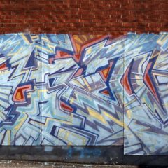Tegelvägg som målats med stor graffitkonstverk.
