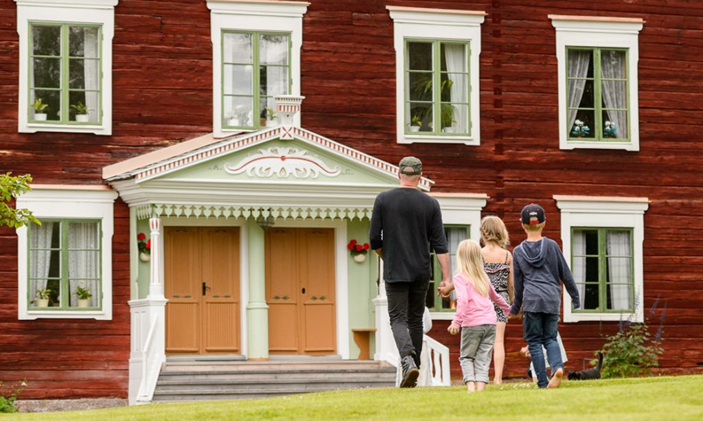 Man och tre barn är på väg in i ett hus.