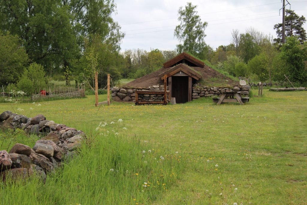 Foto på rekonstrerat järnåldershus med ingång på kortsida.