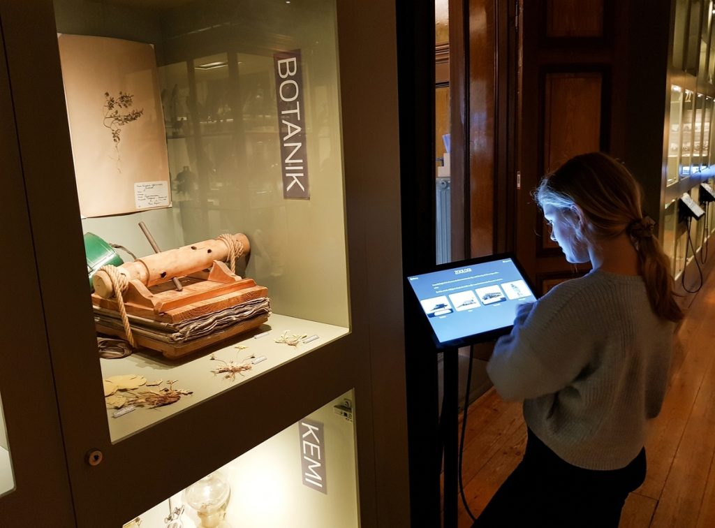 Ett barn tittar på en skärm framför en museimonter