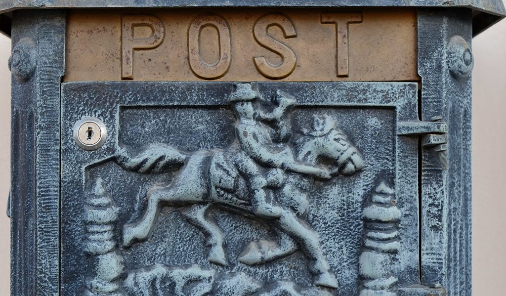Postlåda med relief av postryttare till häst.