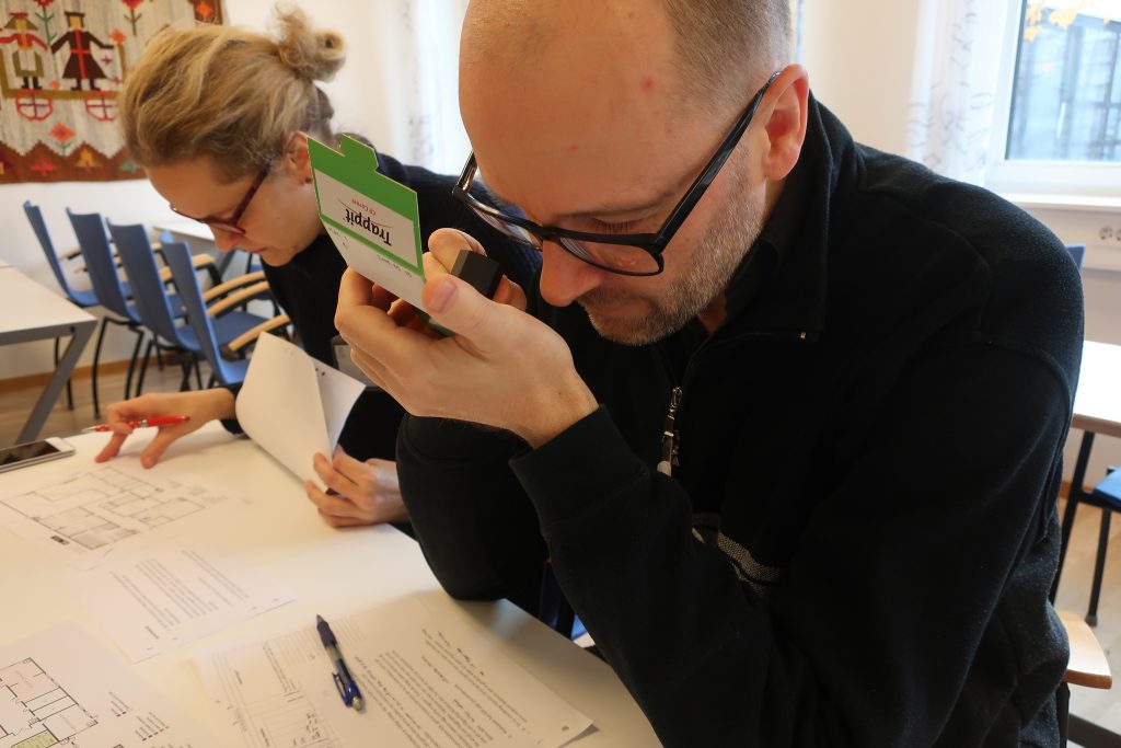 Två personer sitter vid bord och studerar skadedjur med hjälp av lupp