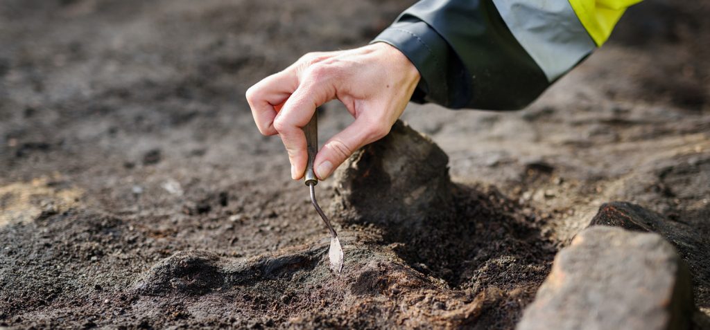 Närbild på hand som petar i jorden med en liten, liten spade