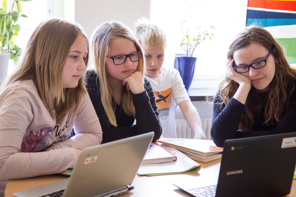 Fyra barn sitter framför datorer.