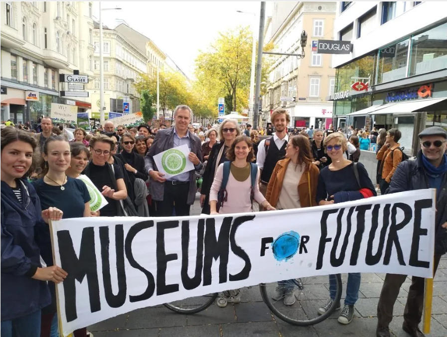 Demonstrationståg med glada deltagare. I förgrunden en vit banderoll med texten Museums for Future.
