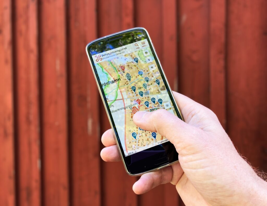 Bild på en hand som håller i en mobil som visar information om bebyggelse med kulturvärden i närheten.