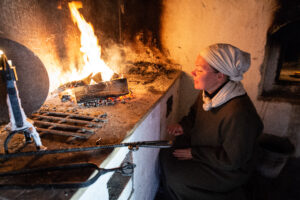 Museilärare värmer sig vid elden i 1600-talsköket.