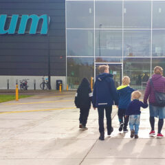 Fyra barn och en vuxen framför entré till ett museum.