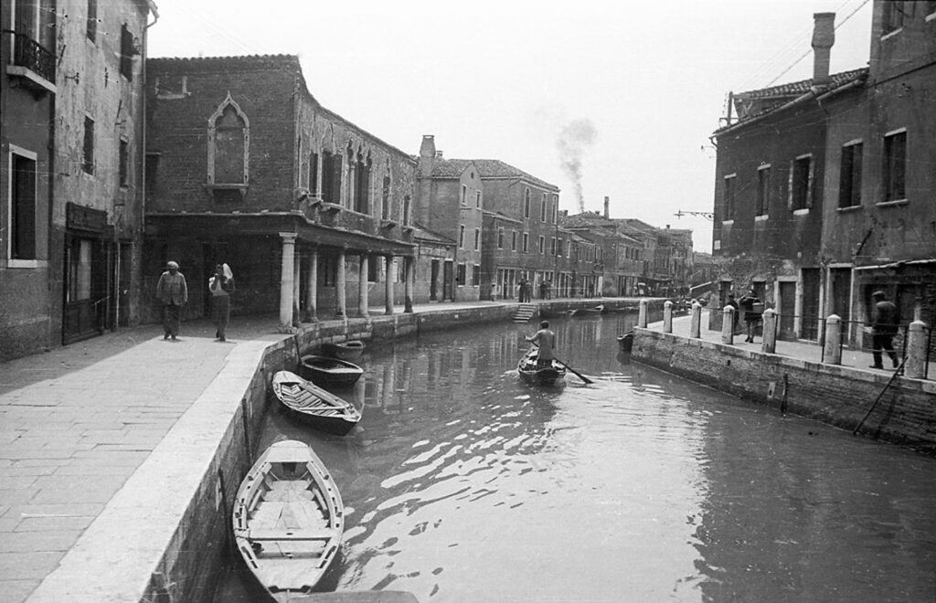 Svartvit bild med kanal och båtar från Venedig.