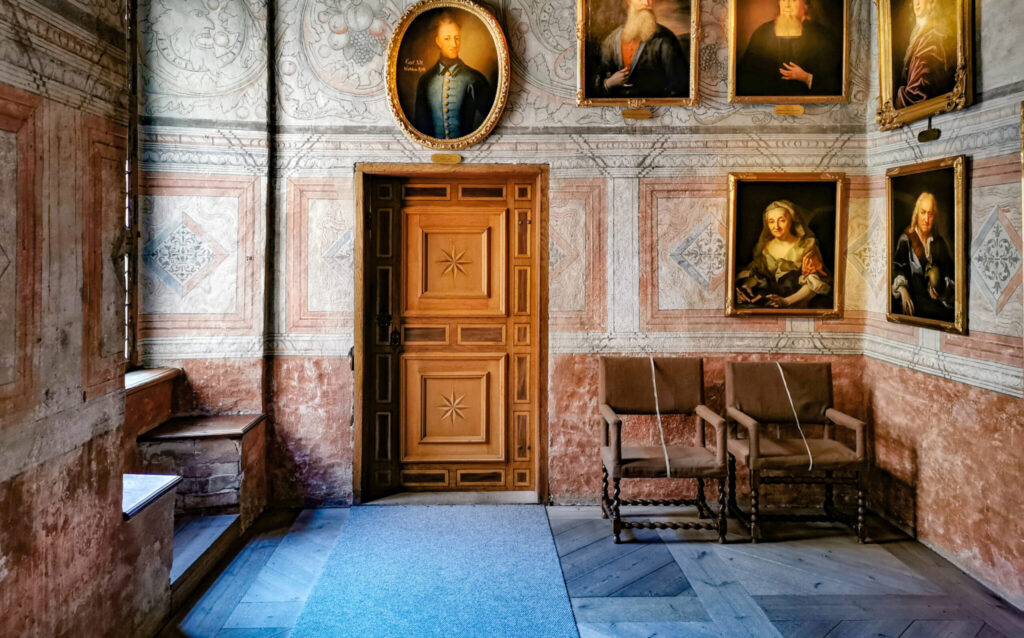 Ett ålderdomligt dom, som taget ur ett slott, med äldre porträtt på väggarna.