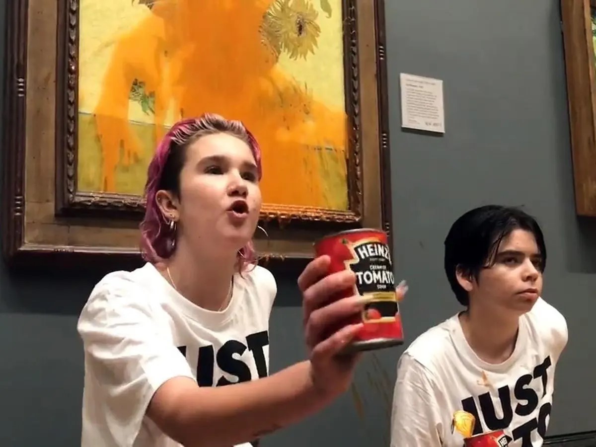 Klimataktion på National Gallery i London i oktober 2022: Två ungdomar har kastat tomatsoppa på en målning av solrosor av Vincent van Gogh och har limmat fast sig i väggen.