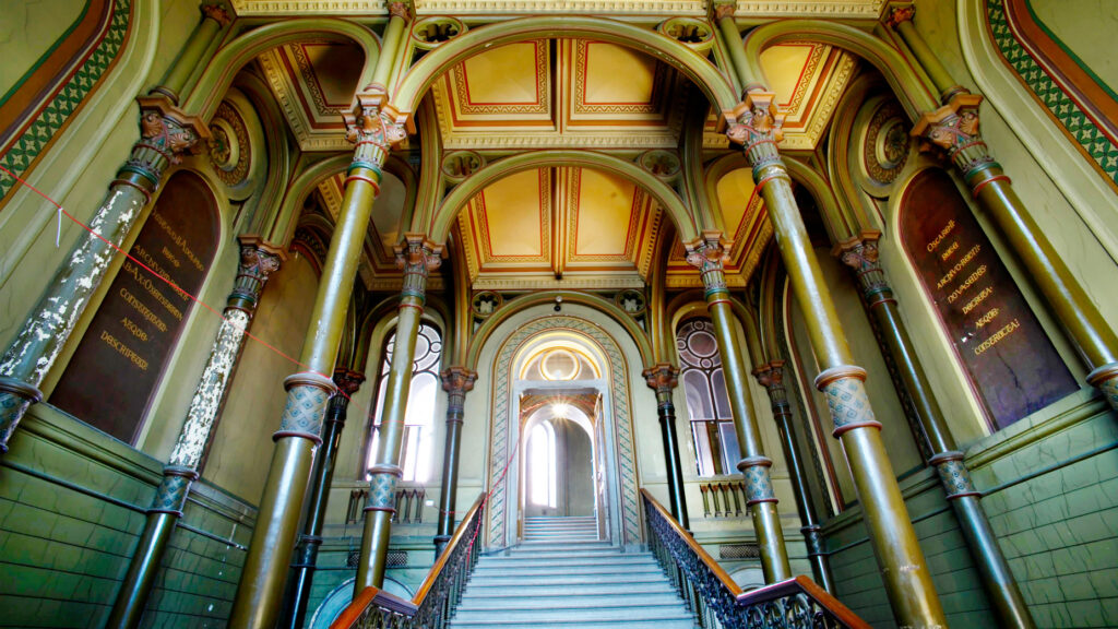 En palatsliknande interiör med trappa, synliga valvbågar och högt till tak.