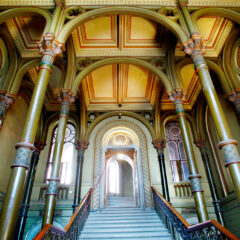 En palatsliknande interiör med trappa, synliga valvbågar och högt till tak.