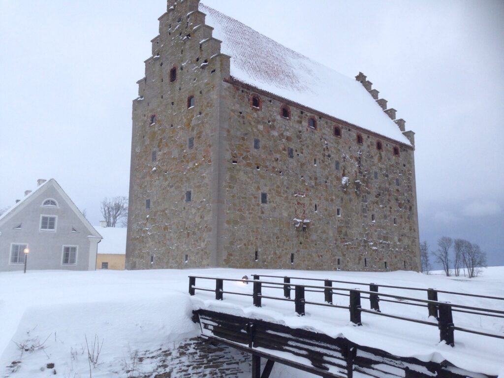 Glimmingehus medeltida borg sedd från vallgraven framför bron med snö på tak och mark.