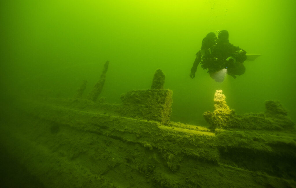 En dykare under vatten utforskar ett vrak.