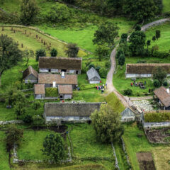 Några äldre hus fotograferade från luften med träd runt omkring.