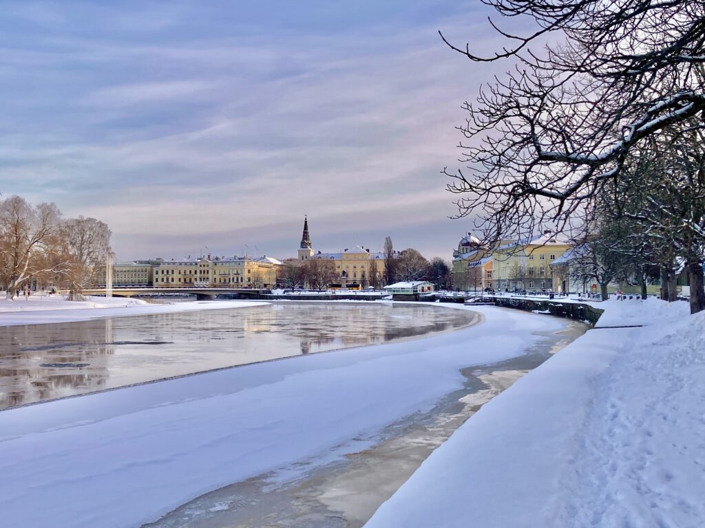 Bilden visar en vy över Karlstad med en kyrka i mitten och vatten i förgrunden.