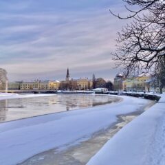 Bilden visar en vy över Karlstad med en kyrka i mitten och vatten i förgrunden.