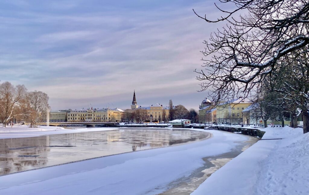 Vy över Karlstad med en kyrka i mitten och vatten i förgrunden.