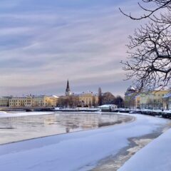 Vy över Karlstad med en kyrka i mitten och vatten i förgrunden.