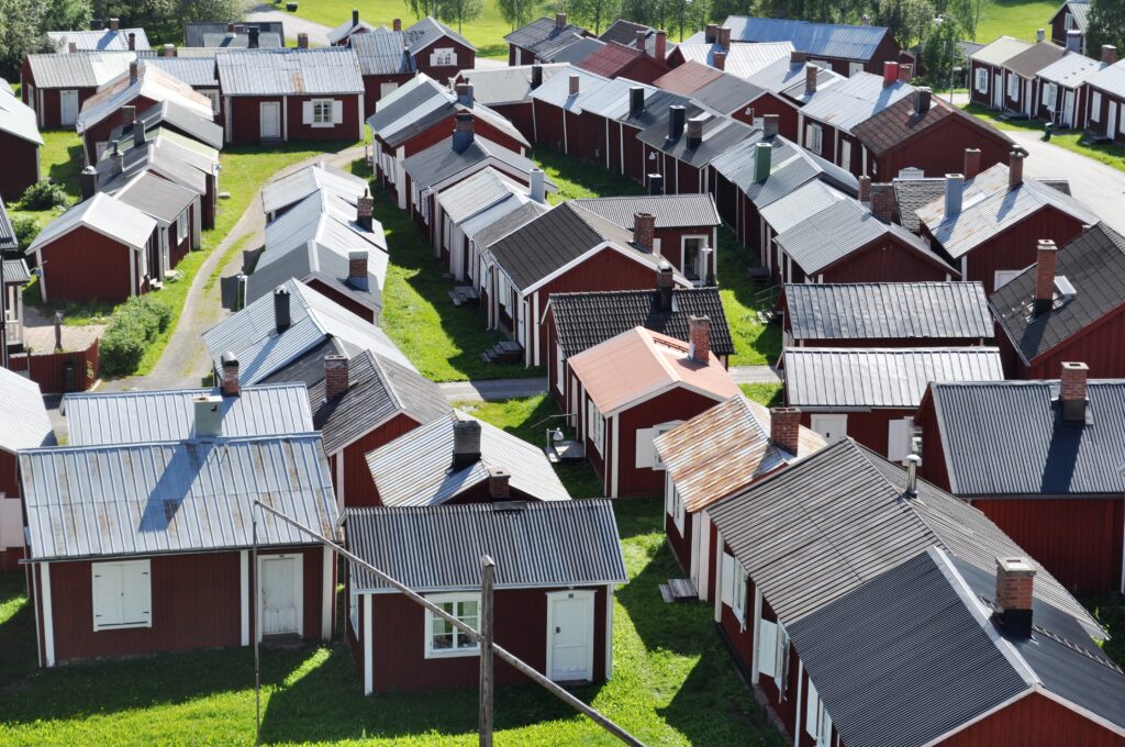 Vy över rödmålande trähus. De flesta hustak är i grå plåt.
